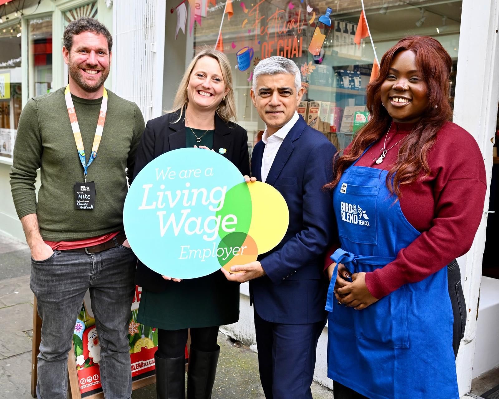 Four people holding a 'we are a living wage employer' sign.
